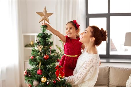 mother and daughter placing star on top of Christmas tree